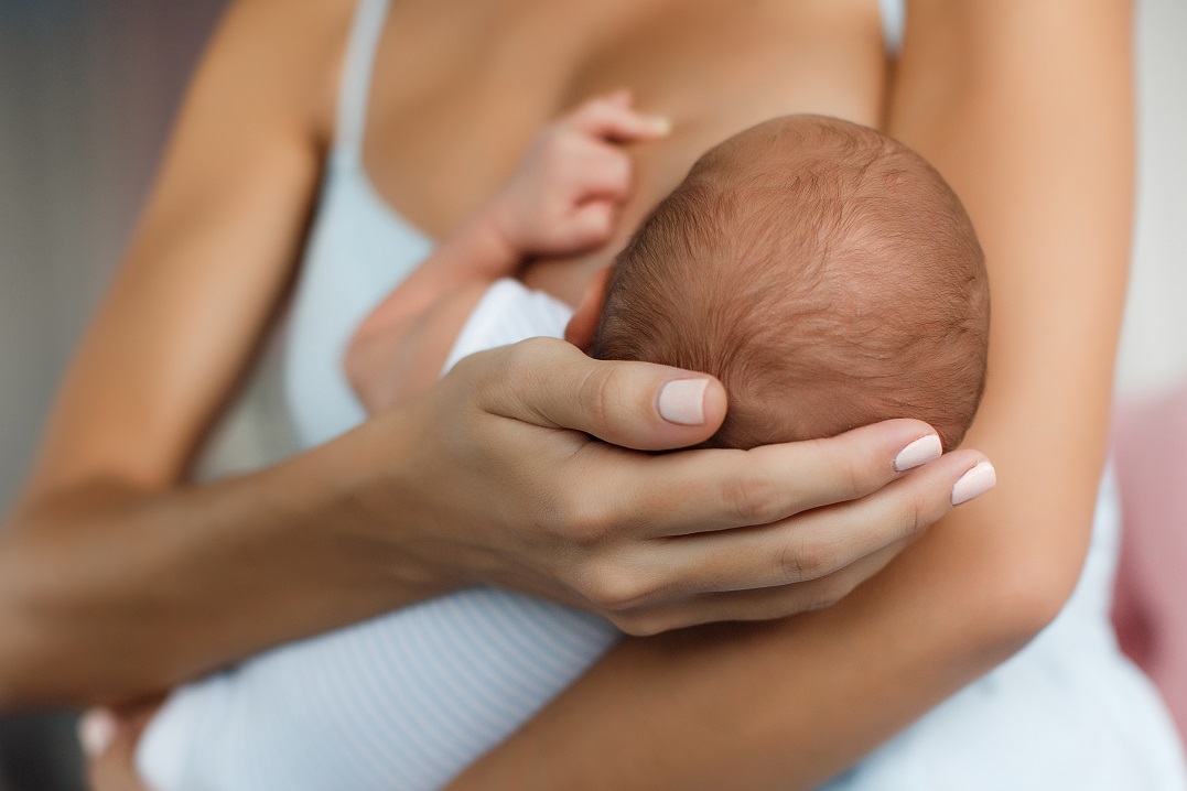 Mother holding a newborn baby for breastfeeding support